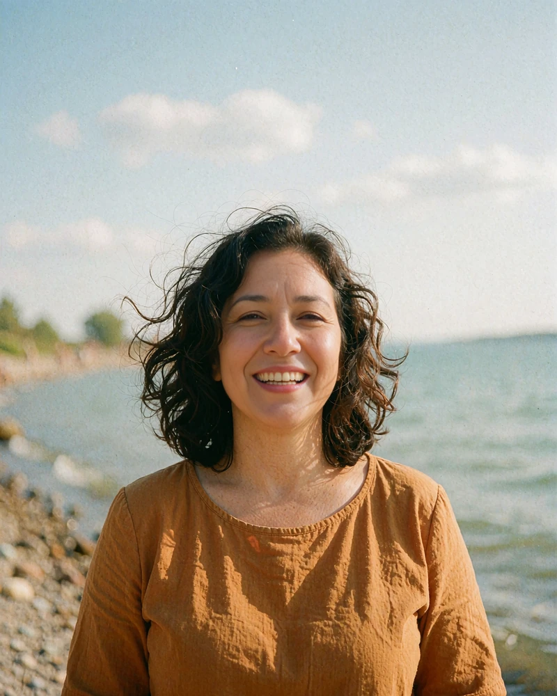 Laughing woman in a mustard top beside a lake on a breezy day, illustrative profile preview for singles over 40